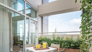 A modern outdoor dining area with a table and chairs, a potted plant, and a view of the city skyline.