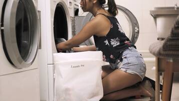 A person operating a front-loading washing machine in a laundry room.