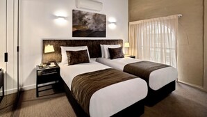 A hotel room with two beds, a large painting on the wall, and a window with curtains. - Quest Newcastle West (Newcastle West)