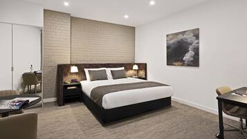 A modern hotel room with a large bed, bedside tables with lamps, a desk, and a chair.