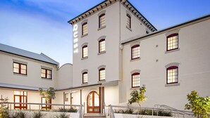 A multi-story building with a central staircase leading to a door marked "QUEST". - Quest Newcastle West (Newcastle West)