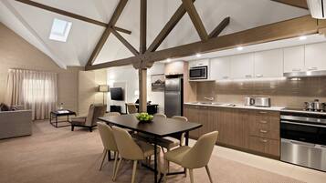 A modern kitchen with built-in appliances, a dining area with a table and chairs, and a living room with a sofa and a TV.