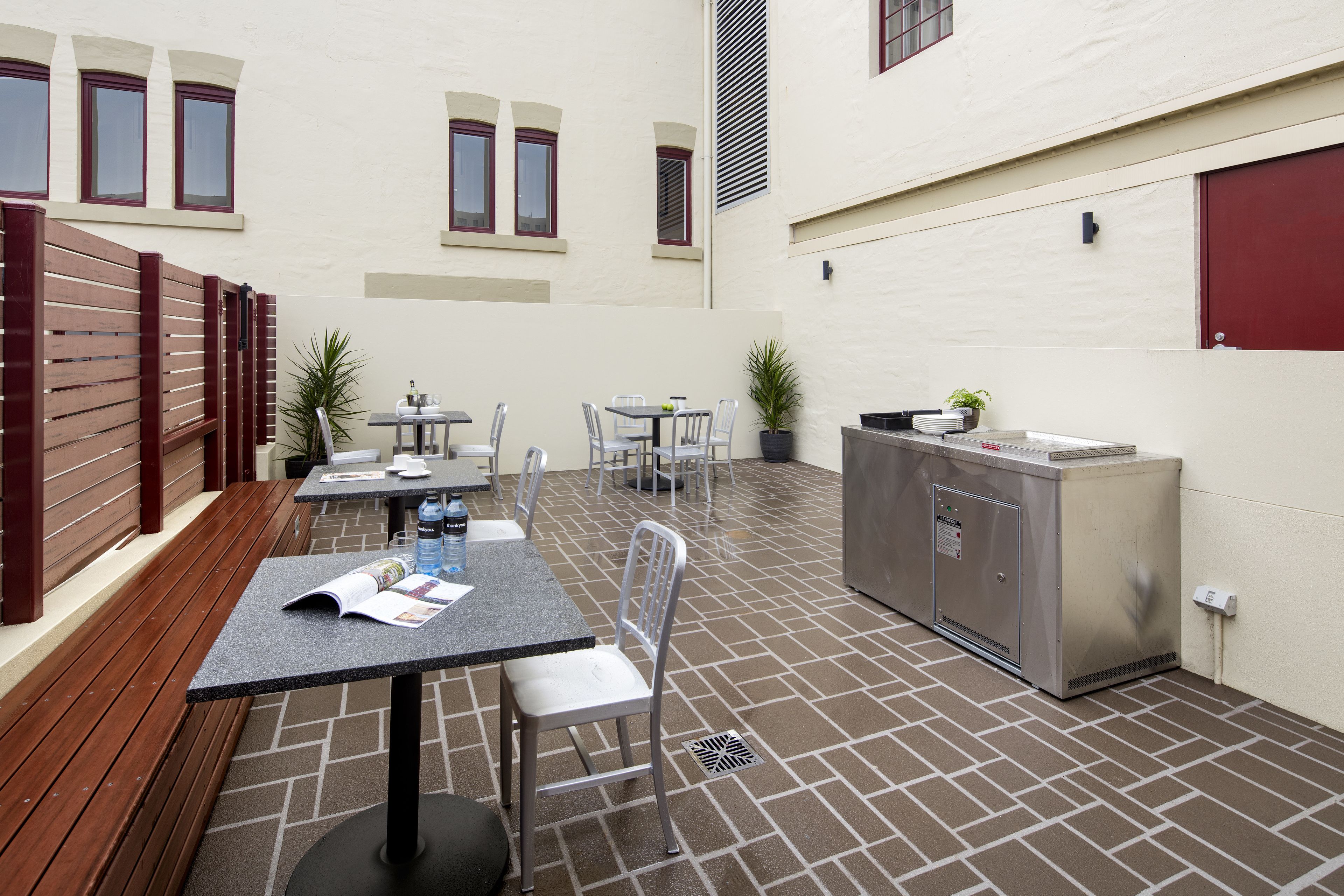 A patio area with a table and chairs, a small kitchen area, and a wooden fence.
