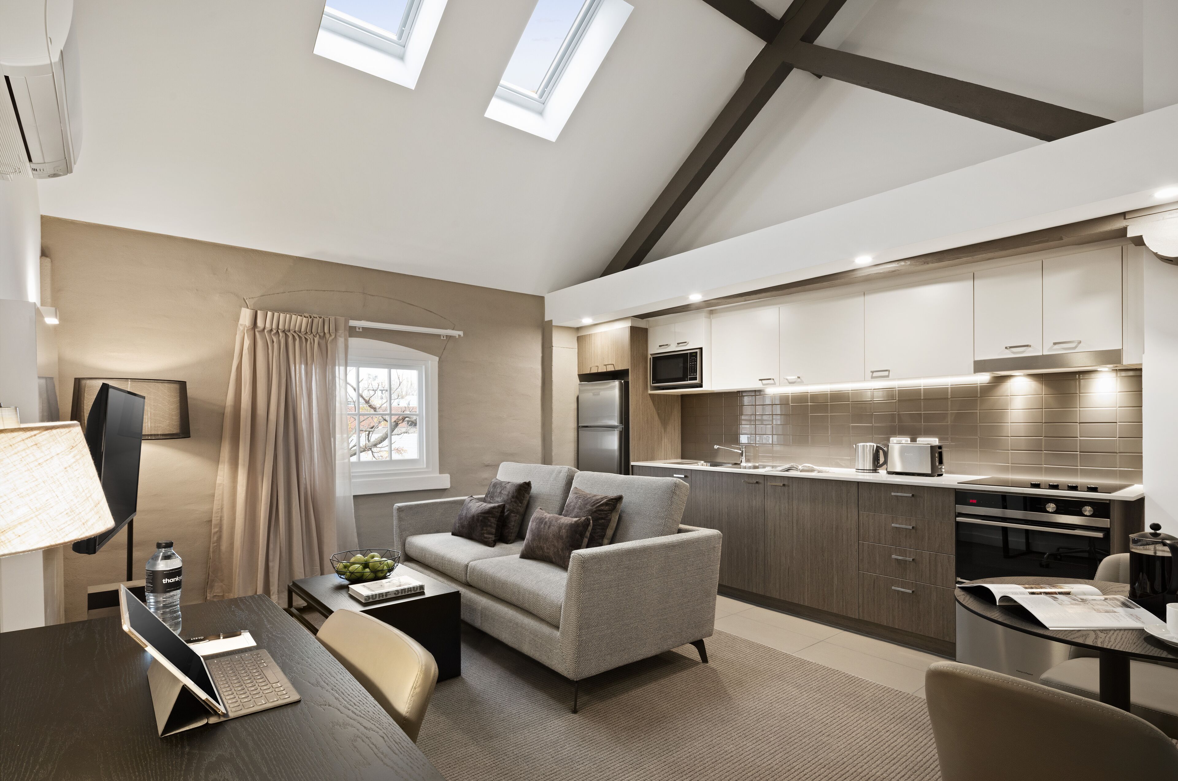 A modern kitchen with built-in appliances, a dining area with a sofa and table, and a TV.