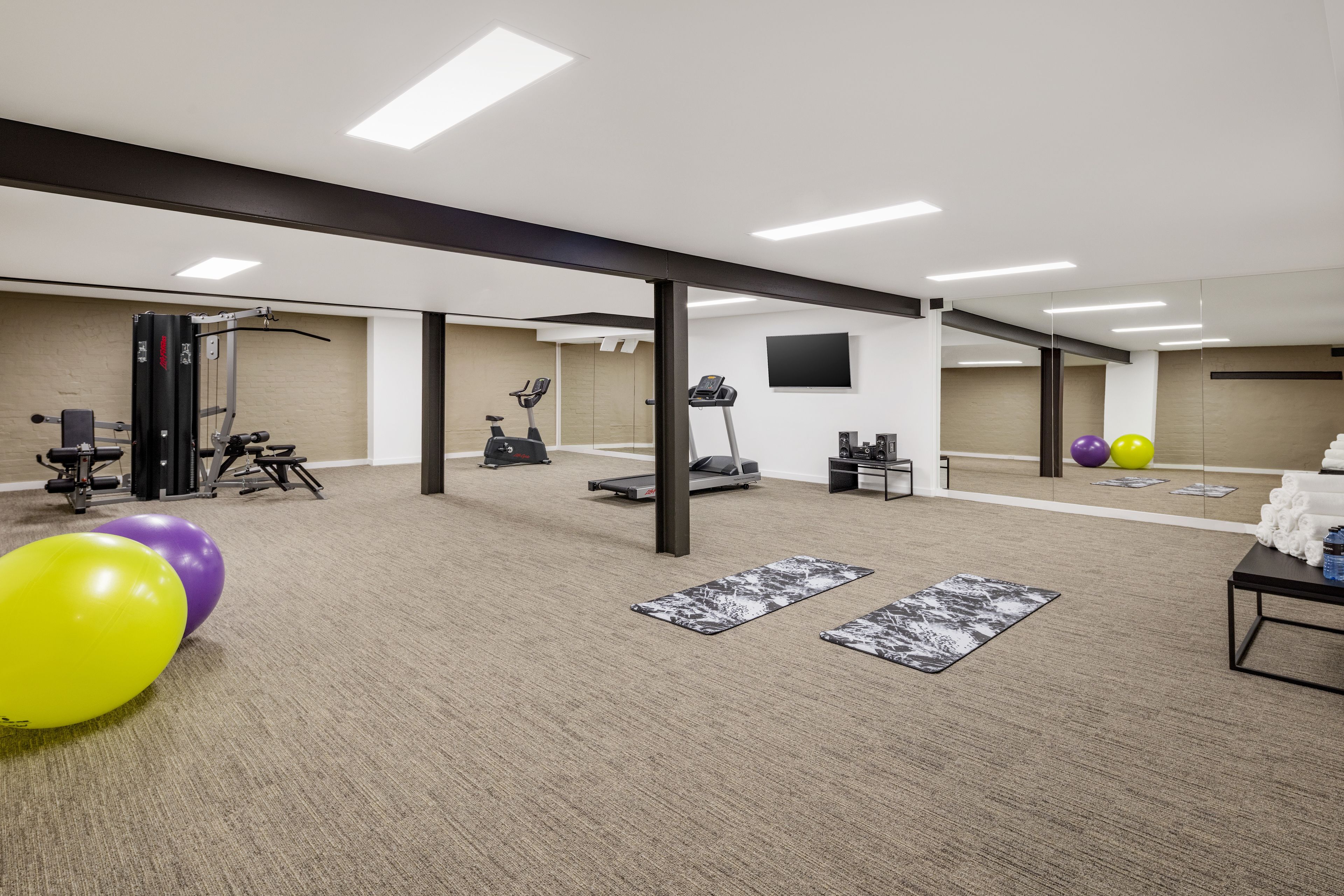 A spacious gym with exercise equipment, yoga mats, and a treadmill.