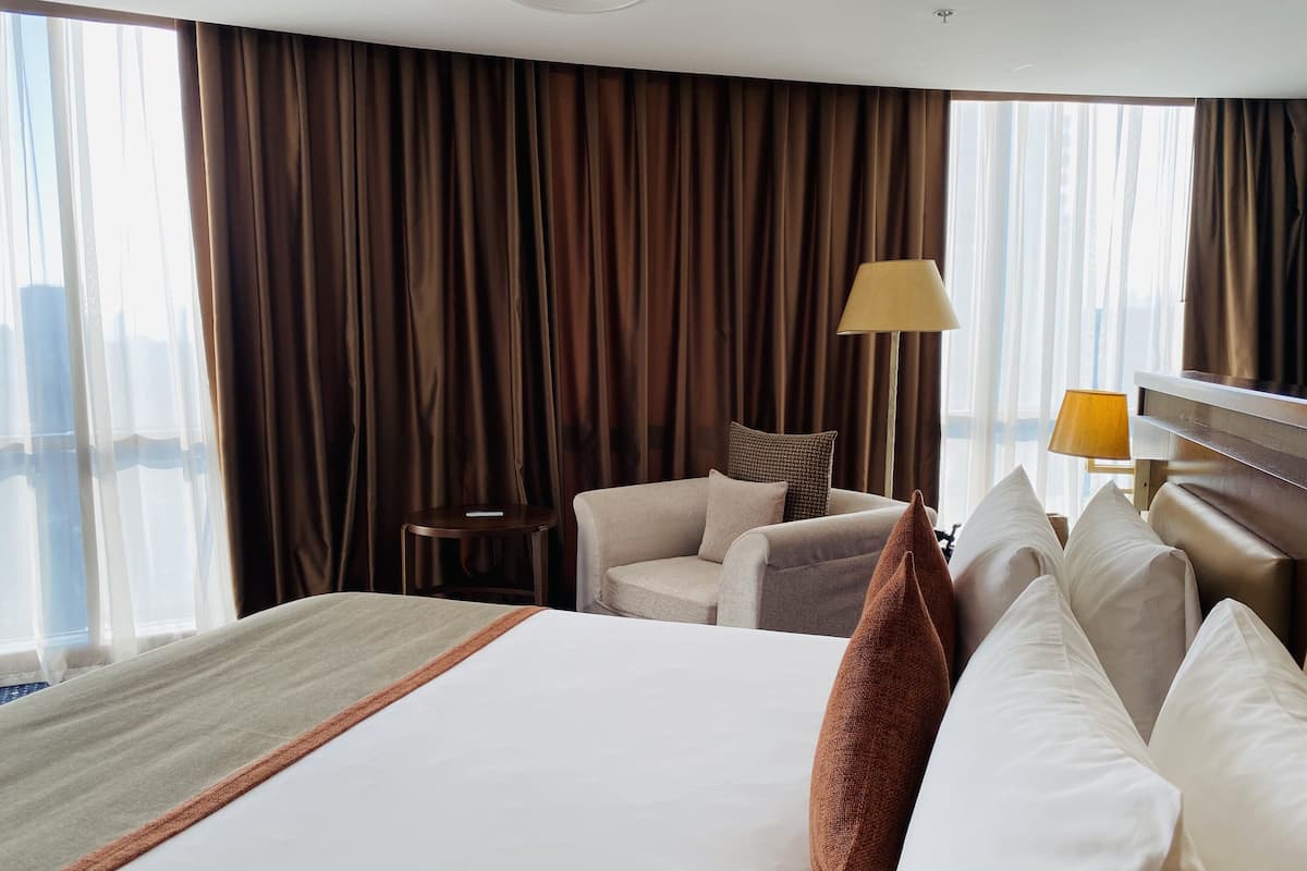 A hotel room with a large bed, a sofa, a small table, and a lamp.