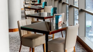 A modern hotel dining area with long tables, chairs, and large windows offering city views. - Parkside Hotel & Apartments (Baku)