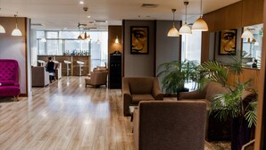 A modern hotel lobby with wooden flooring, multiple seating areas, and large windows. - Parkside Hotel & Apartments (Baku)