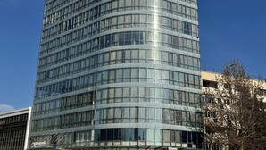 A modern hotel with a curved glass facade, multiple floors, and a prominent sign at the top. - Parkside Hotel & Apartments (Baku)