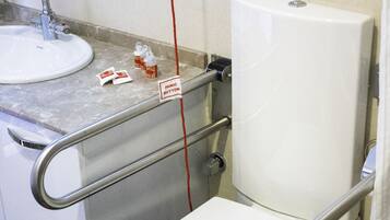 A bathroom with a white toilet, a sink, and a mirror. There is a red cord hanging from the mirror.