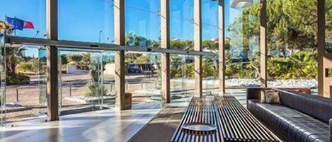 Um interior moderno com grandes janelas, um banco de madeira e um sofá.