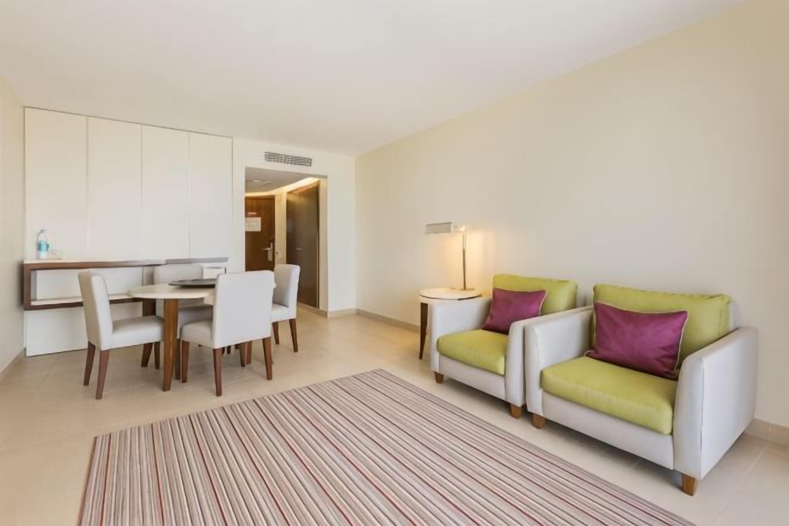 Un salon moderne comprenant un coin repas, un ensemble de canapés et une petite table avec une lampe.