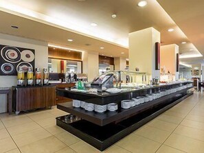 Ein Buffetbereich mit verschiedenen Speisen und Getränken, eine Kaffeestation und eine Theke mit einer Kasse.