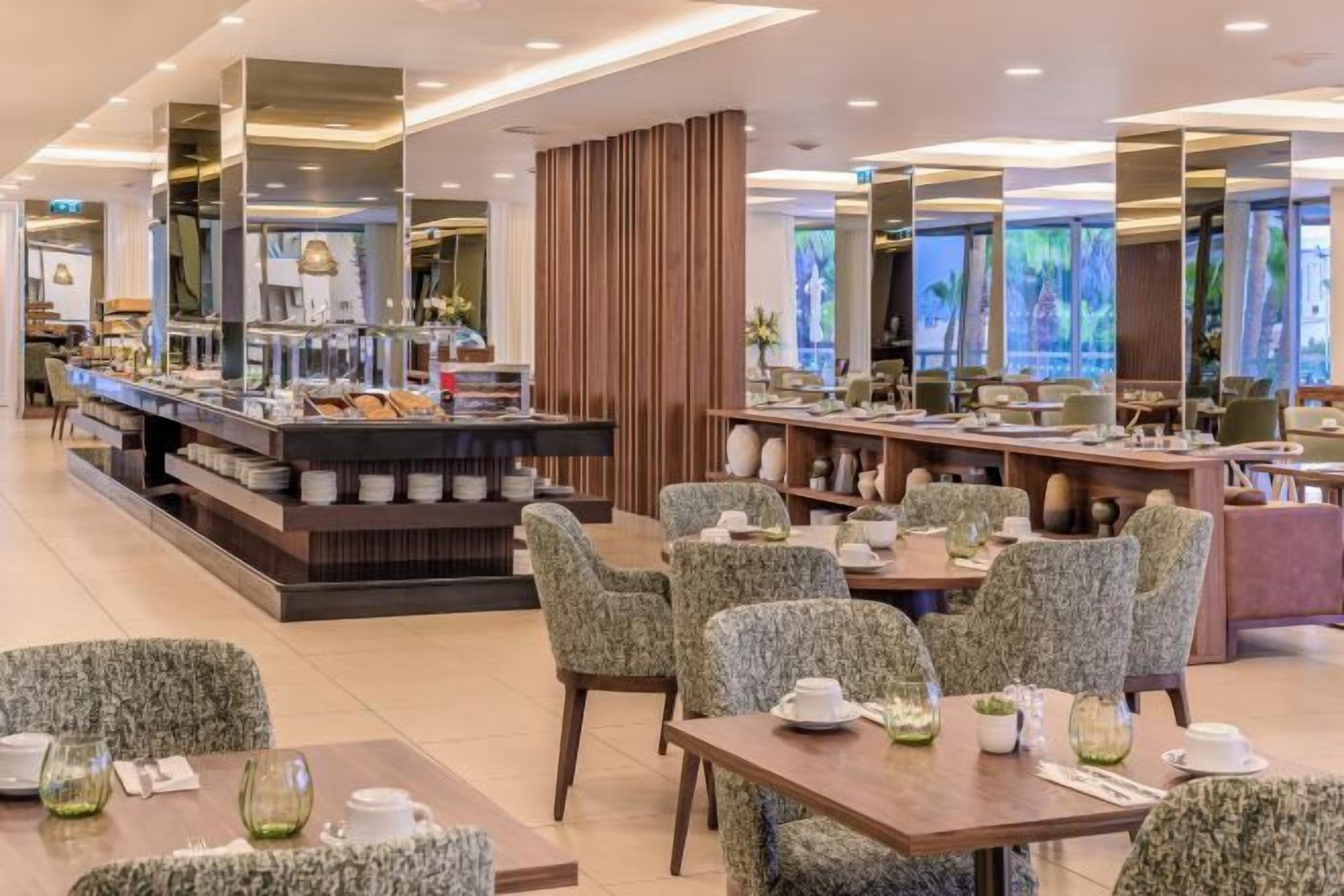Ein modernes Restaurant mit einem Buffetbereich, verschiedenen Sitzgelegenheiten und Blick ins Freie.