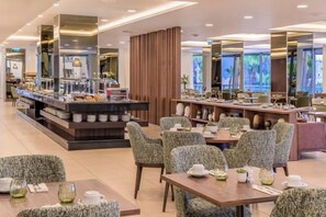 A modern restaurant with a buffet area, multiple seating options, and a view of the outdoors.