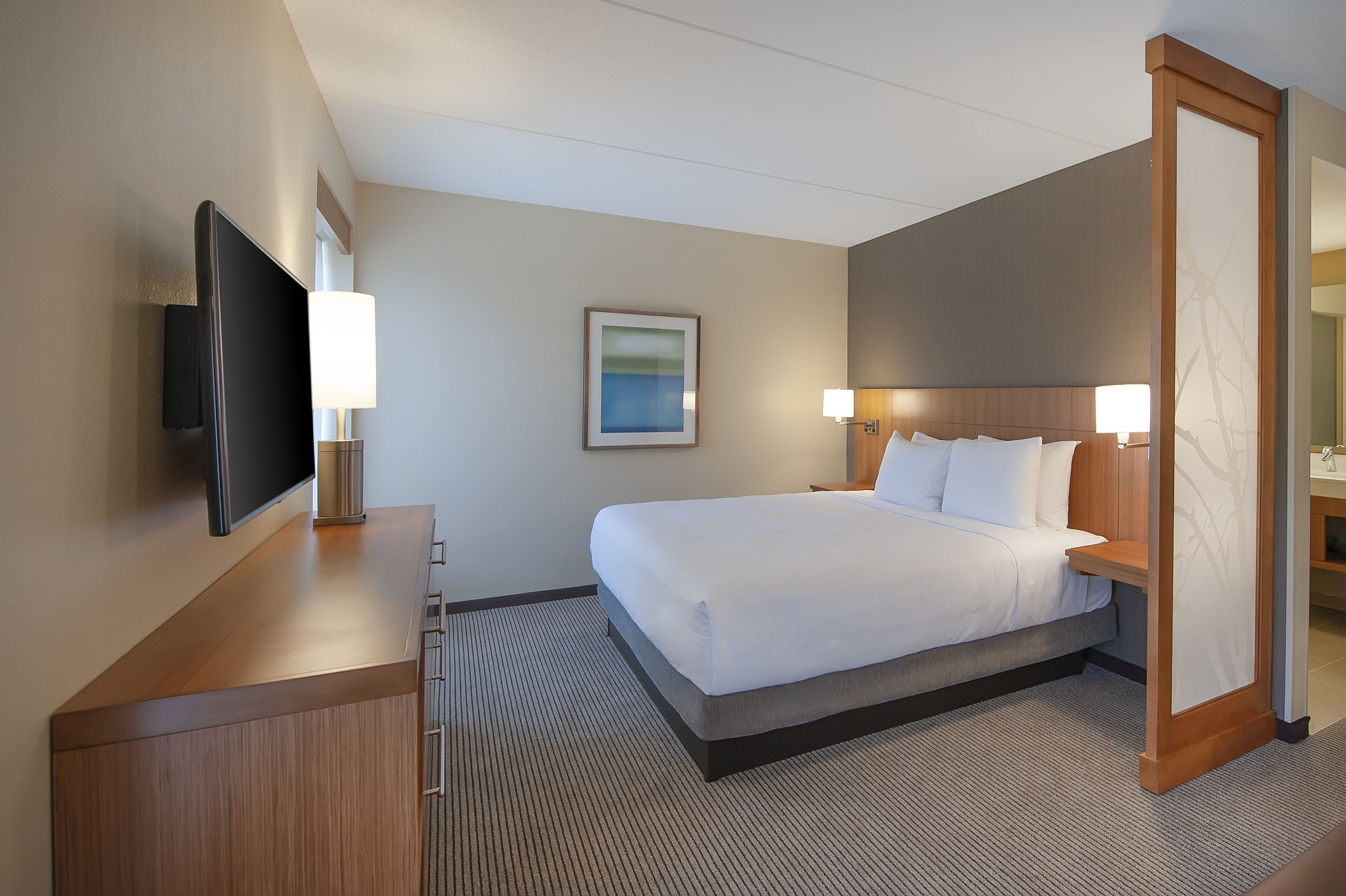 Une chambre d’hôtel avec un lit, une télévision, un bureau et une lampe.