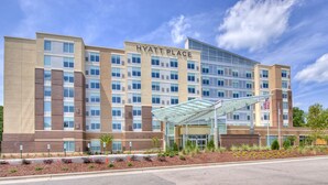 A multi-story hotel with a modern design, featuring a prominent entrance with a glass canopy and an American flag.