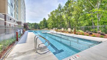 Una piscina al aire libre, sillones reclinables de piscina