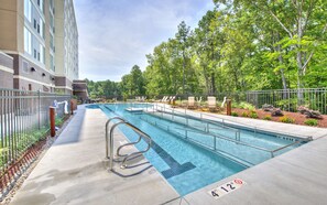 Une piscine dont la profondeur maximale est de 4,12 mètres, entourée d’une terrasse avec des chaises longues et une clôture.