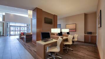 A modern hotel lobby with a reception desk, seating area, and a large window providing a view of the outside.