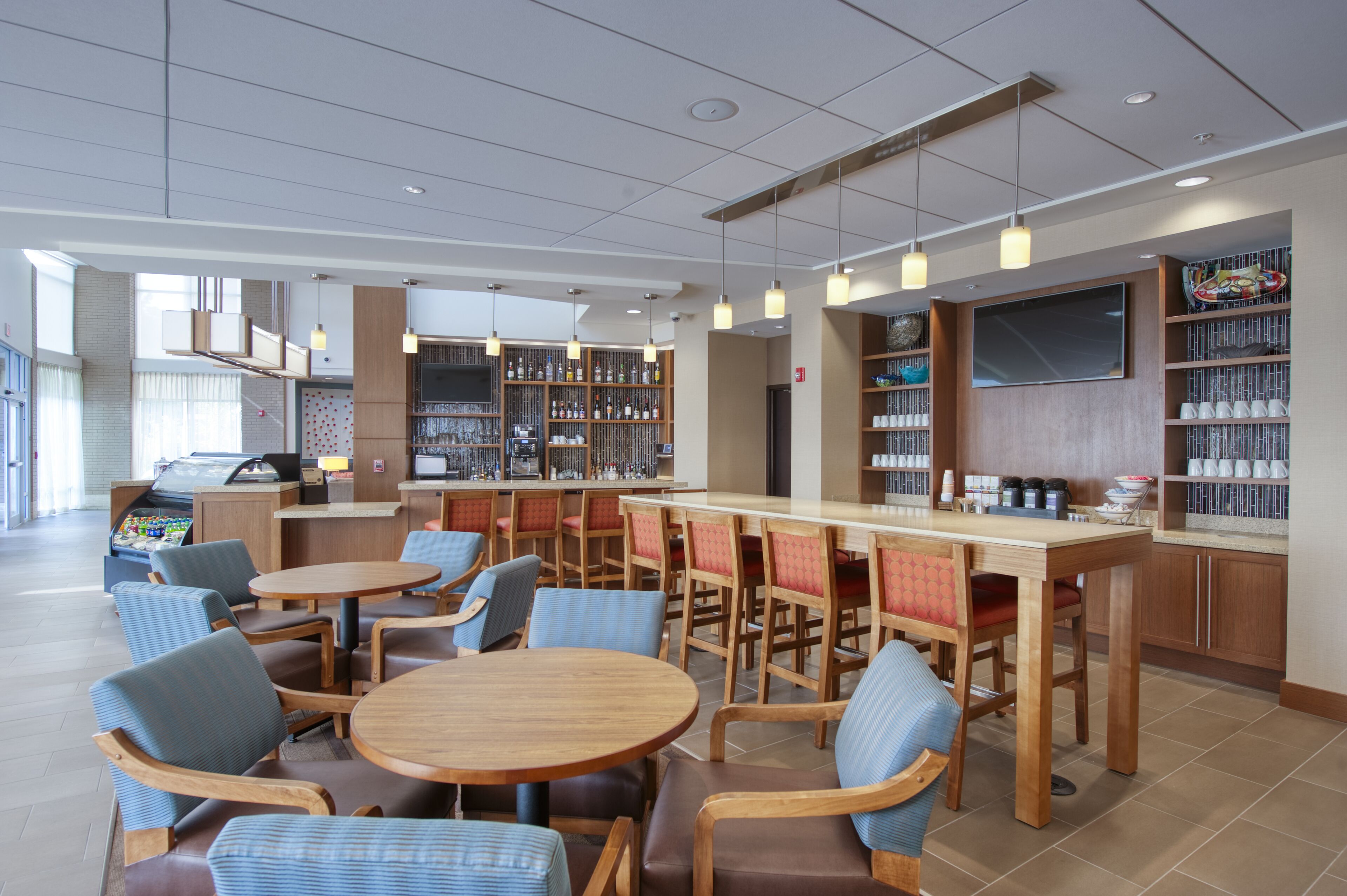 Un café moderne doté de plusieurs espaces de détente, d’un bar et de nombreuses étagères à livres.