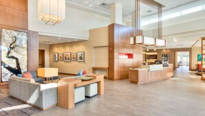 A spacious lobby with a reception desk, seating area, and artwork on the walls.