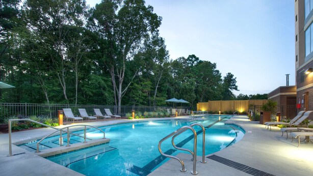 A swimming pool with lounge chairs and a wooden fence.