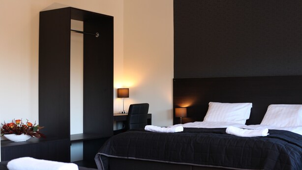 Une chambre d’hôtel avec deux lits, un bureau, une chaise et un téléviseur fixé au mur.