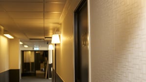 Un couloir d'hôtel avec un mur orné de motifs, une porte portant le numéro « 21 » et une lampe.