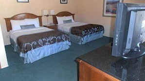 A hotel room with two beds, a desk, and a television. - Budget Host (Trinidad)