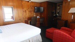 A room with a bed, a desk, a television, and a red sofa.