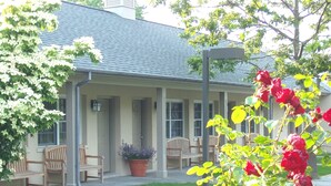 A covered patio area with outdoor seating, a potted plant, and a well-maintained lawn. - Southampton Long Island Hotel (Southampton)