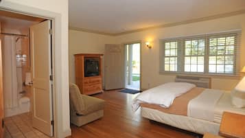 A bedroom with a bed, a wooden cabinet, a television, and a door leading to a bathroom.