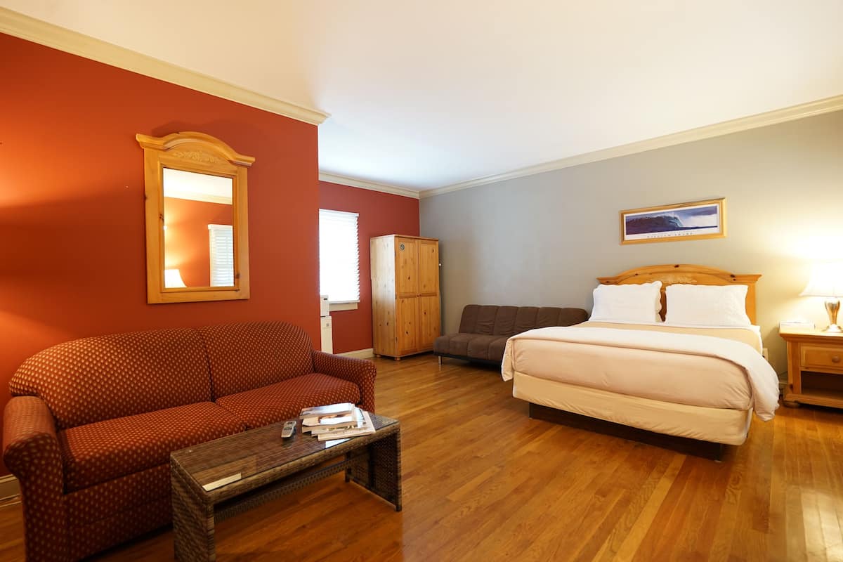 Ein Hotelzimmer mit Bett, einer Couch, einem Holzschrank und einem kleinen Tisch.