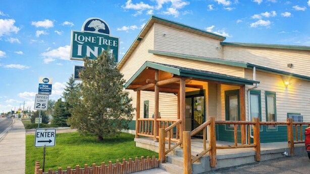 A lodge with a covered entrance, a sign indicating 'Lone Tree Inn,' and a speed limit sign of 25 mph.