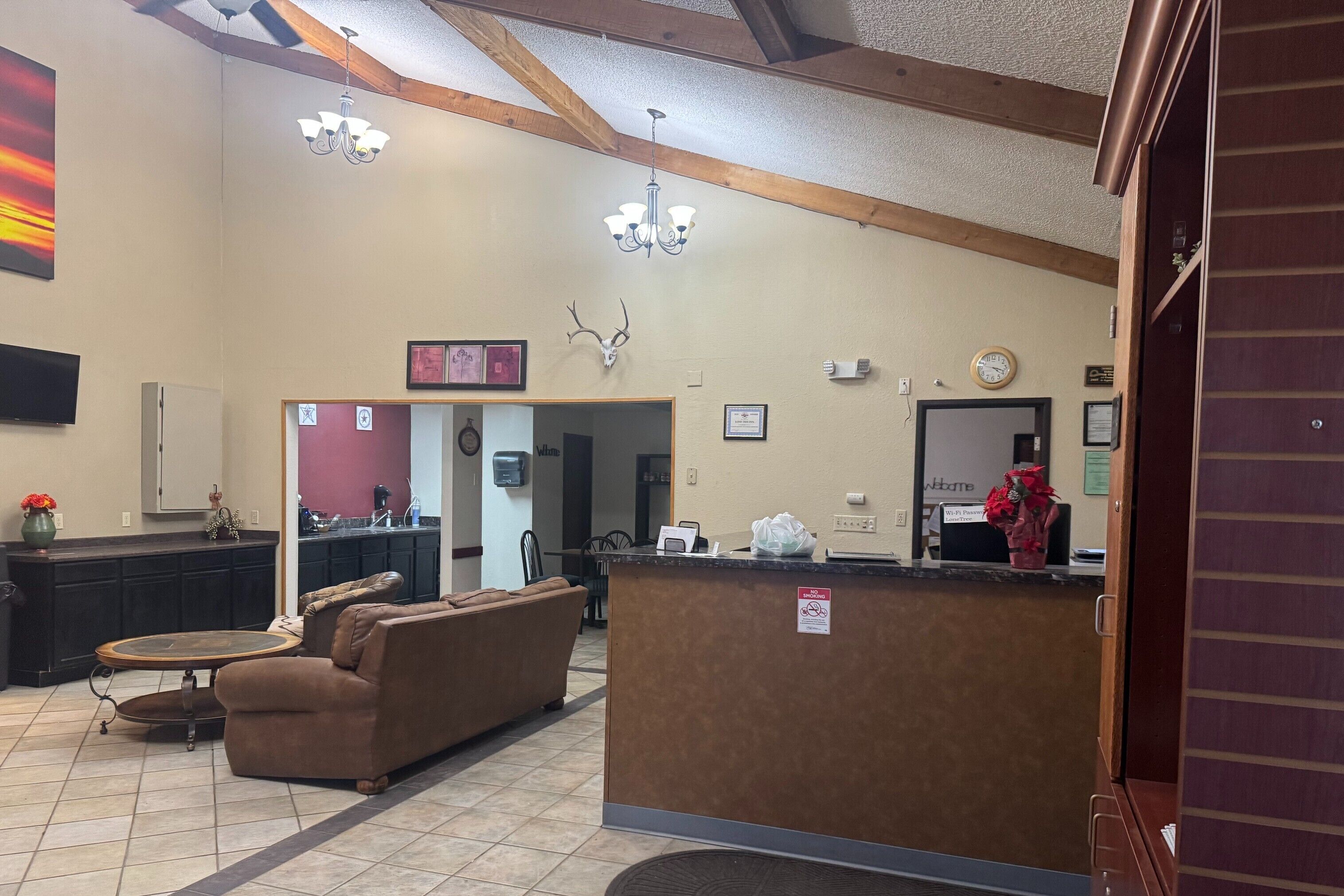 A lobby with a reception desk, a sofa, a coffee machine, and a TV mounted on the wall.