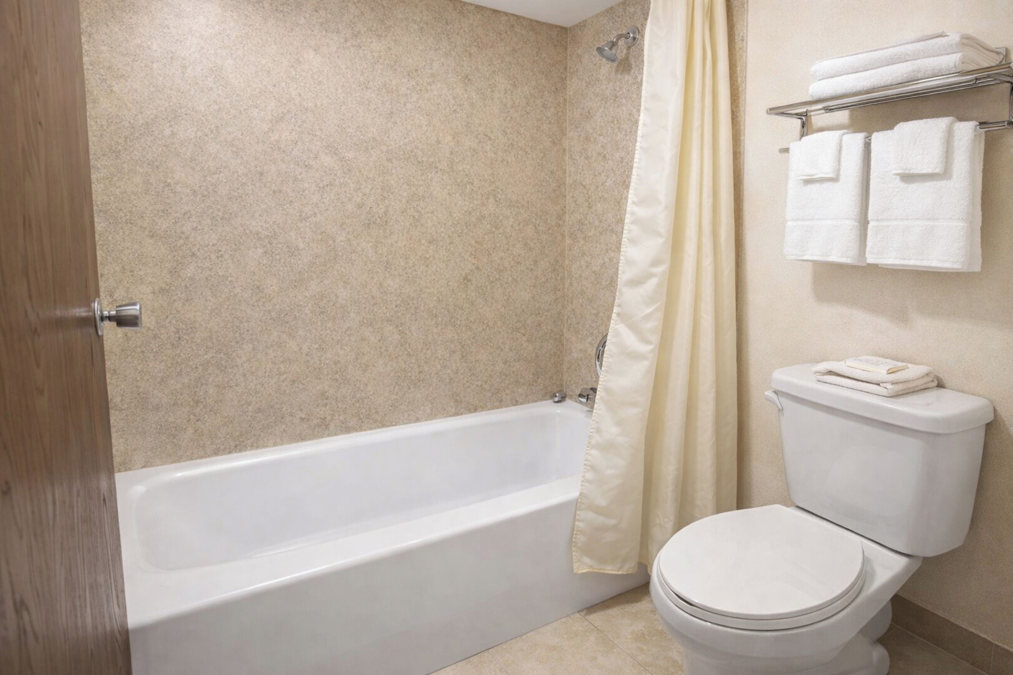 Un baño con bañera, inodoro y toallero con toallas.