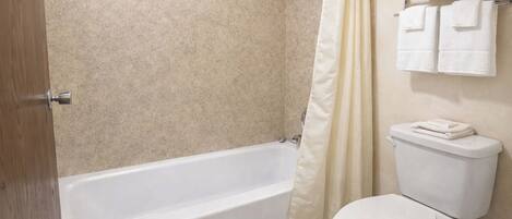Un baño con bañera, inodoro y toallero con toallas.