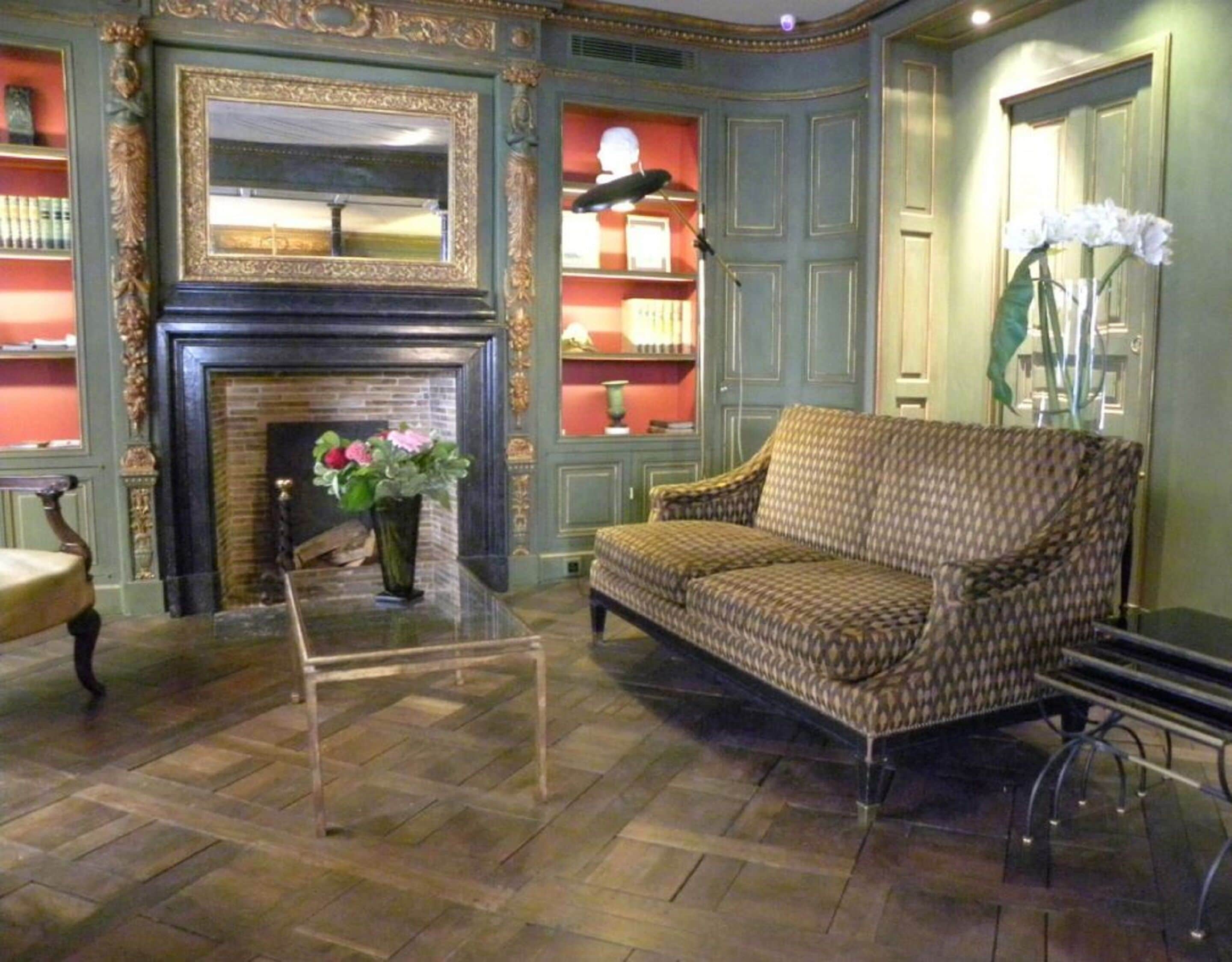 A room with a patterned sofa, a fireplace, and a mirror.