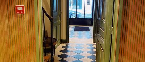 A hallway with a checkered floor, a statue, and a staircase.