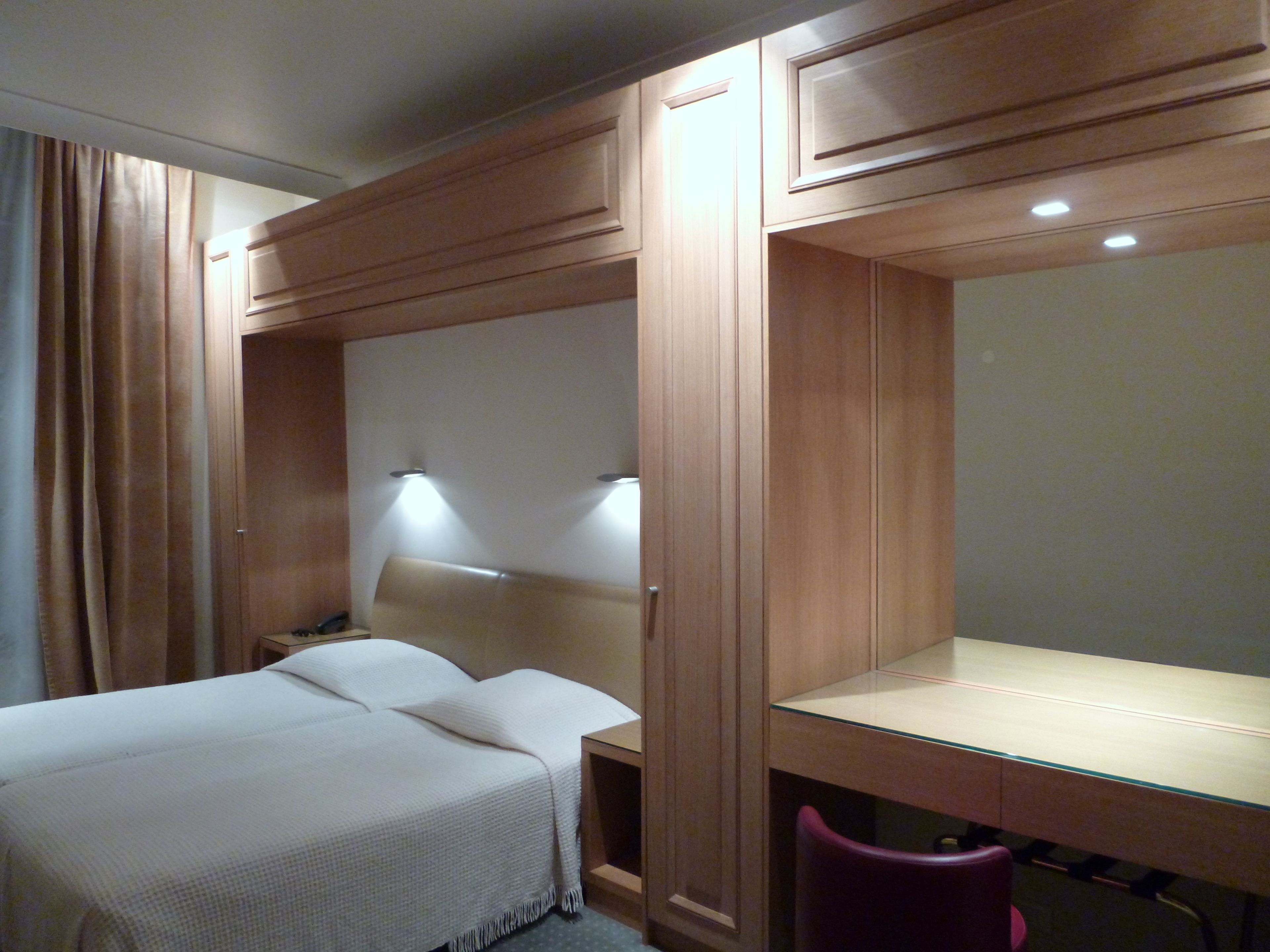A hotel room with a bed, a desk, and a chair.