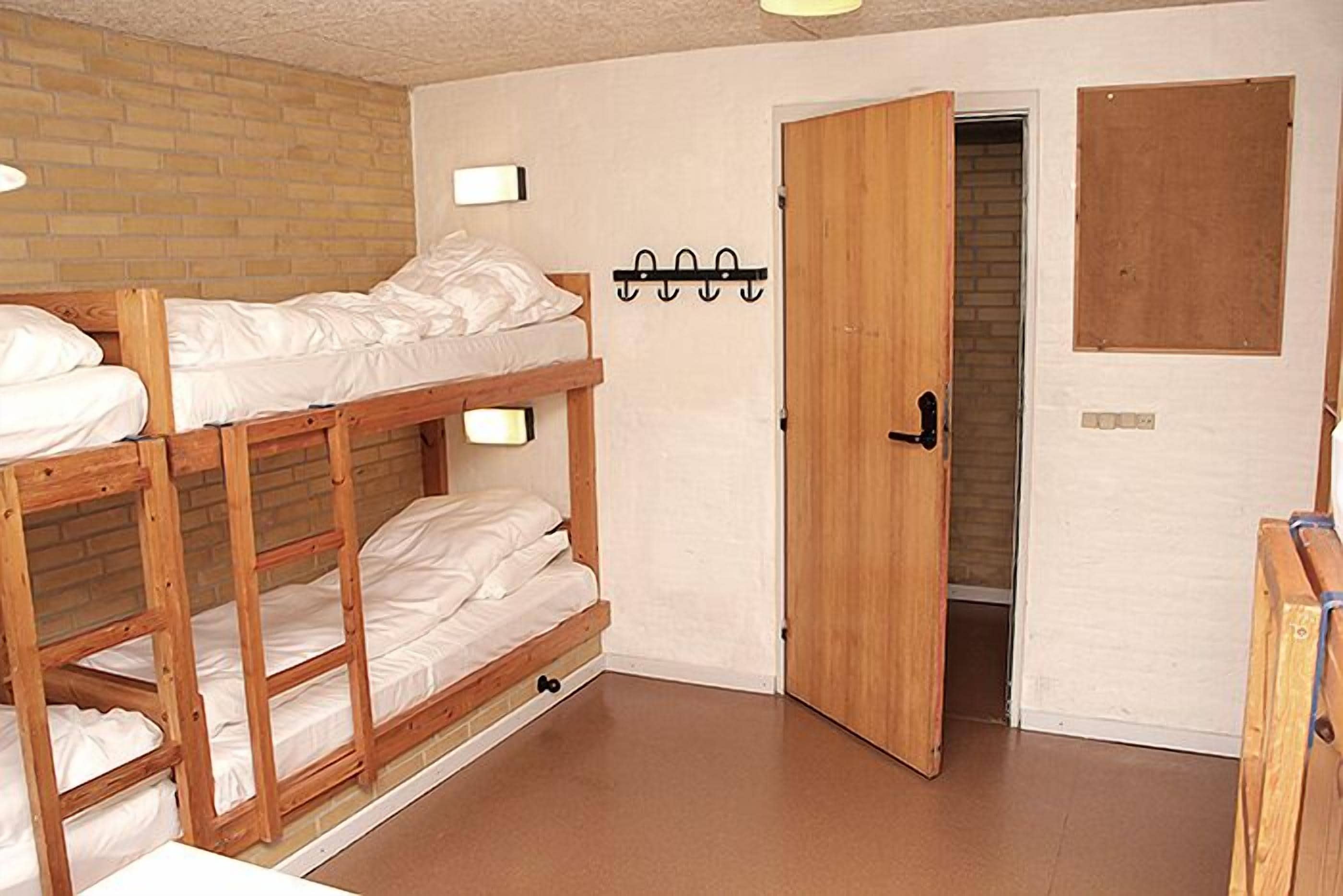 Una habitación con literas, una puerta de madera y un interruptor de luz en la pared.