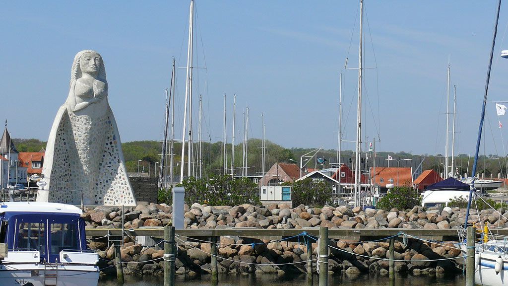 A marina with boats, a large statue, and a building with a red roof.