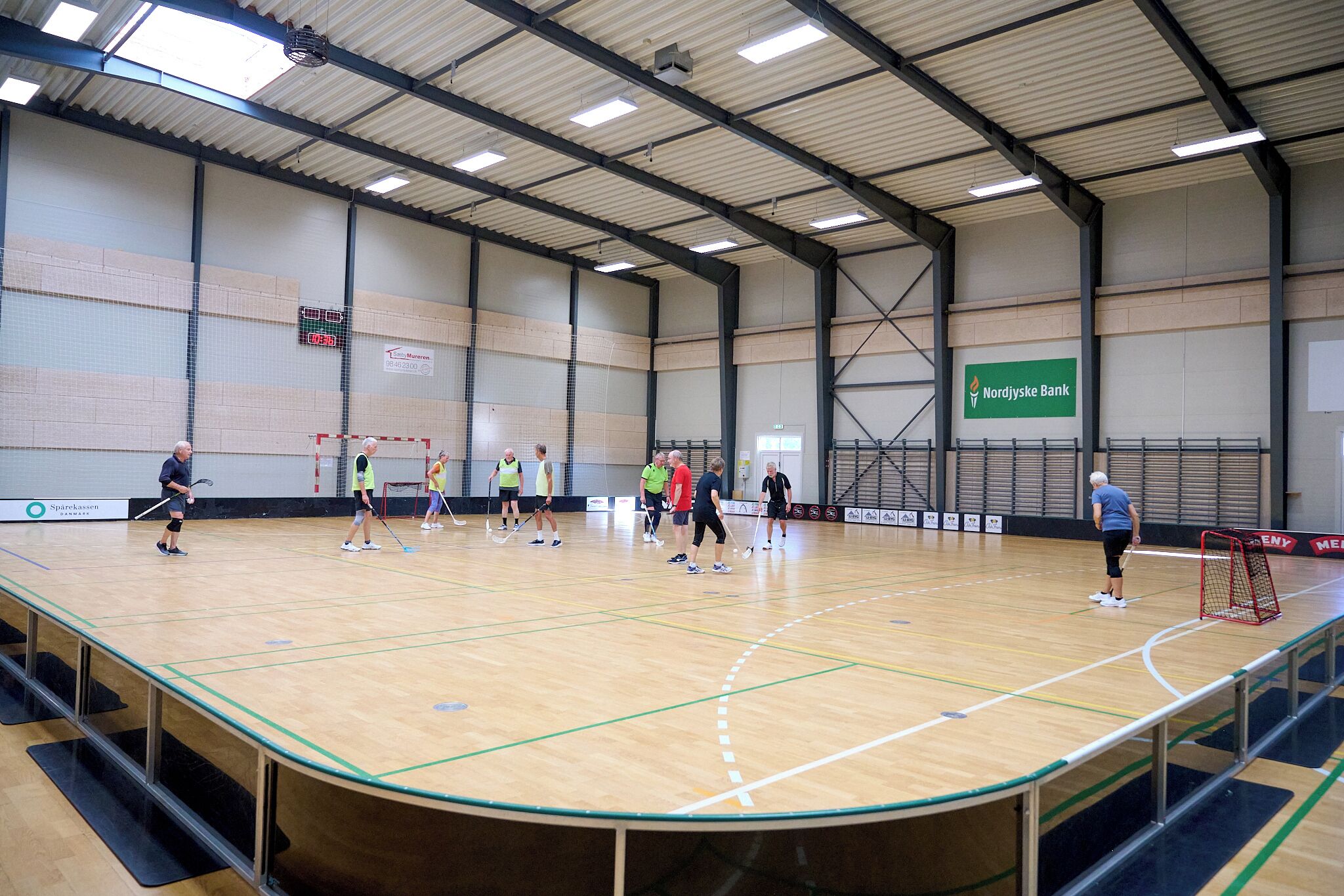 Una palestra al coperto con campo da basket, porta da hockey e un tabellone segnapunti ben visibile.