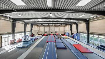 Un gimnasio amplio con varios equipos de ejercicio y colchonetas dispuestas para entrenamientos.