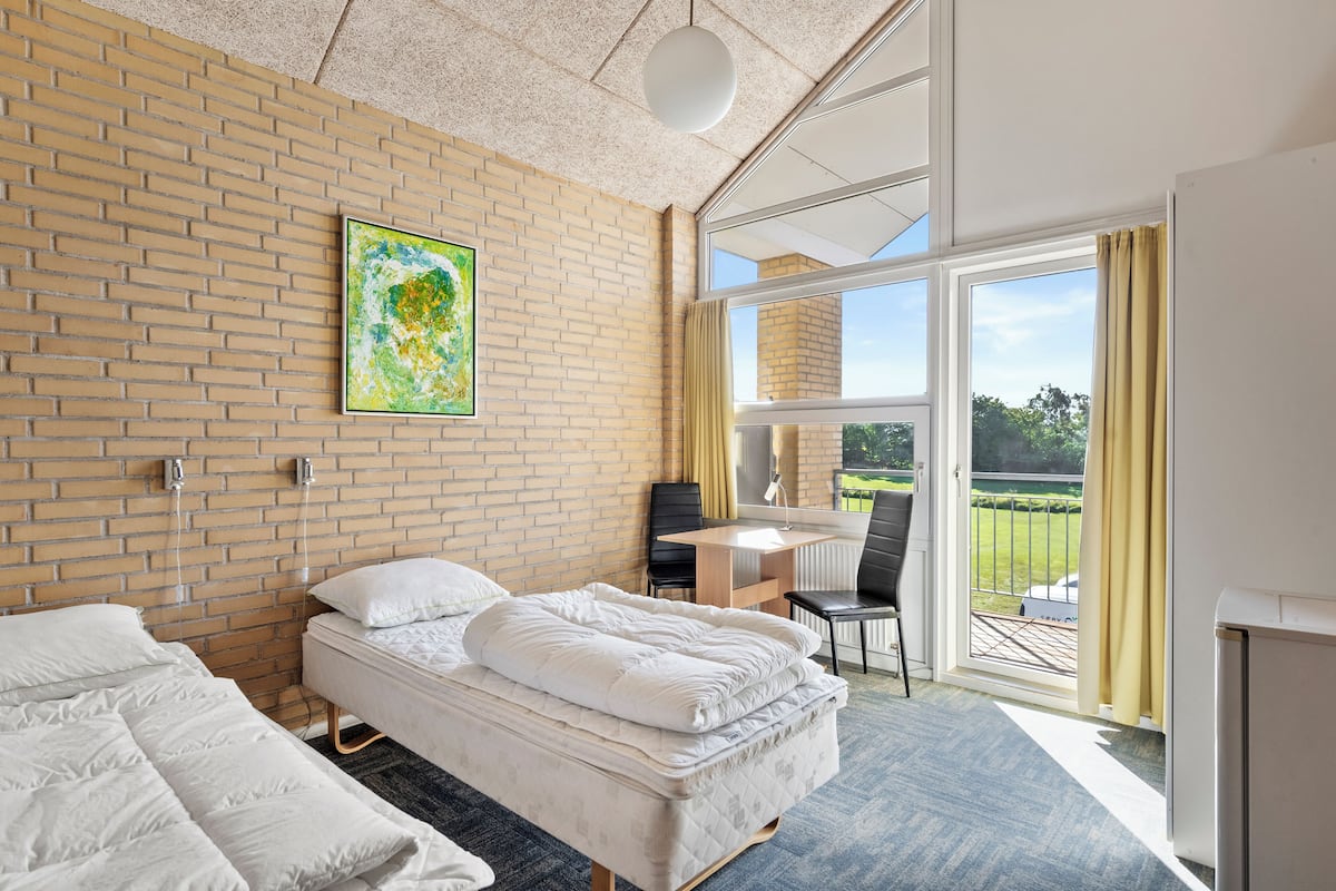 Habitación de hotel con pared de ladrillo, una cama, un escritorio y vistas al exterior.