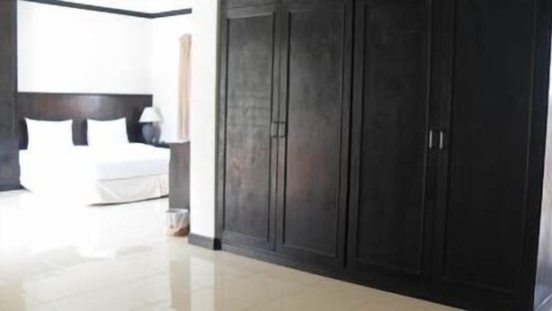 A bedroom with a large wardrobe, a bed, and a bedside table. - Kamala Phuyai Resort (Kamala)