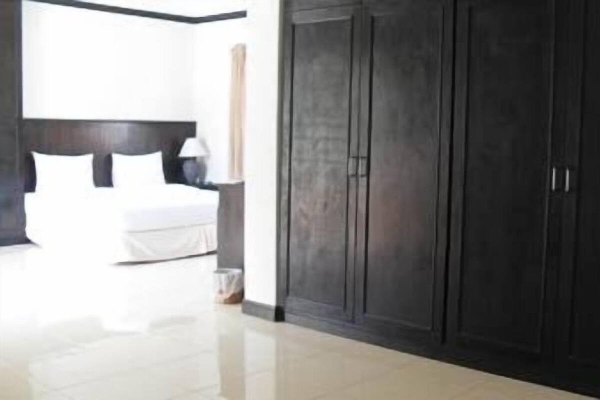 A bedroom with a large wardrobe, a bed, and a bedside table.