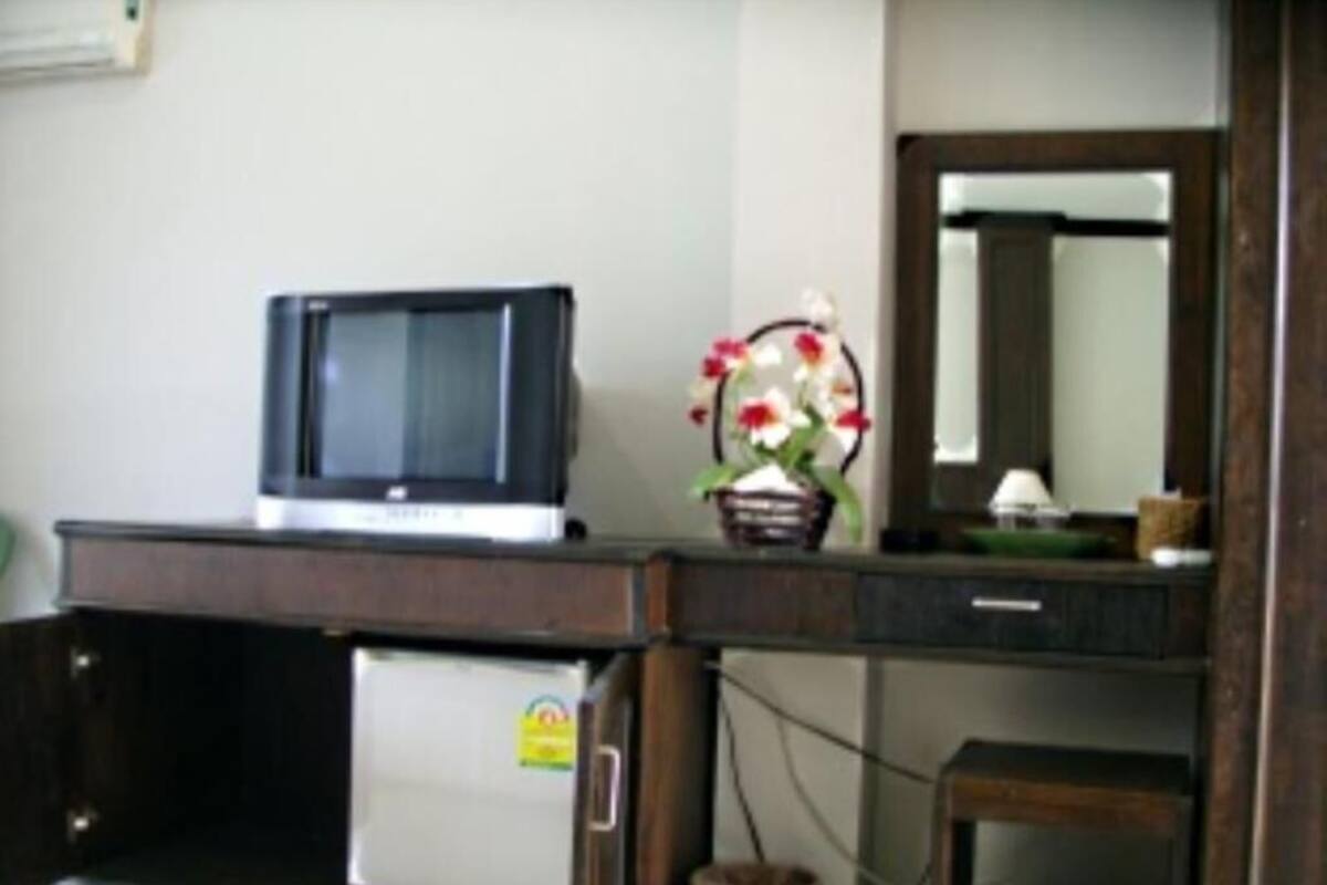 A room with a desk, a microwave, a small refrigerator, a basket with flowers, and a mirror.