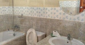 A bathroom with a bathtub, toilet, sink, and a mirror. - Kamala Phuyai Resort (Kamala)